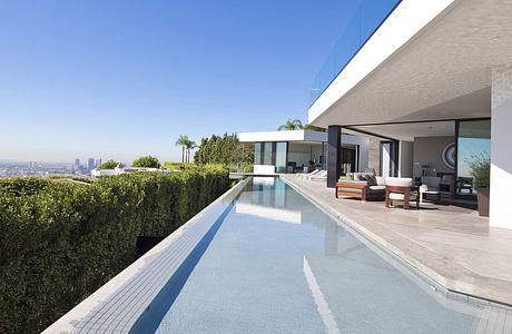 Contemporary home with infinity pool overlooking a cityscape.