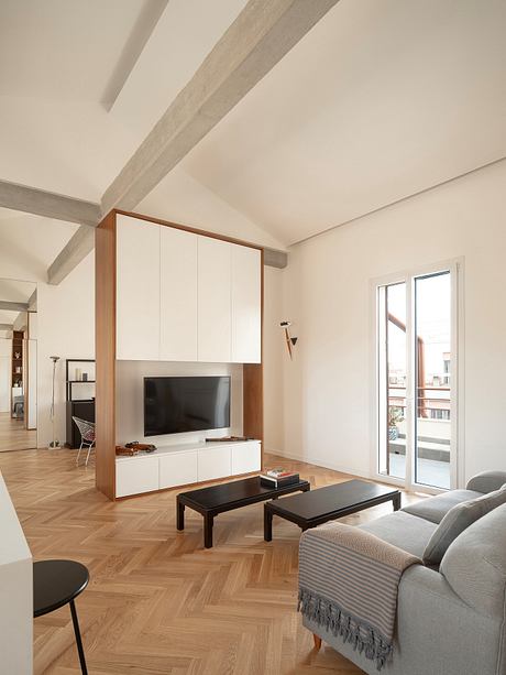 Modern living room with beamed ceiling, wooden floor, and minimalistic furniture.