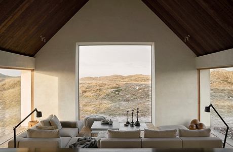 Minimalist living room with large window overlooking a hilly landscape.