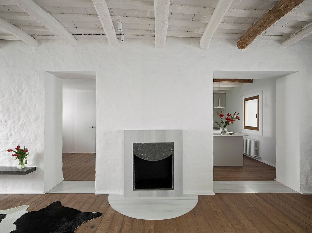 Minimalist interior with central fireplace, wooden floors, and white walls.