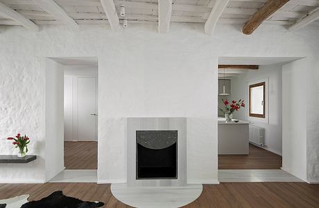 Minimalist interior with central fireplace, wooden floors, and white walls.