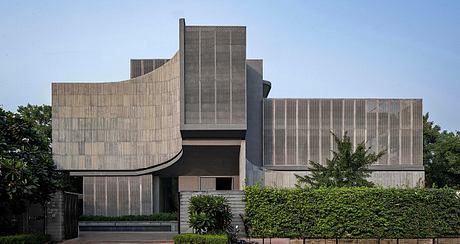 Contemporary building with curved concrete facades and greenery.