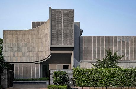 Contemporary building with curved concrete facades and greenery.