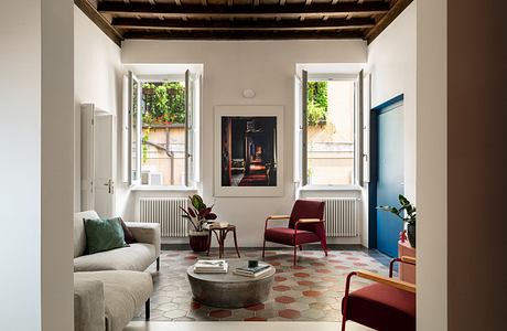 Modern living room with exposed beams, tiled floors, and stylish furniture.