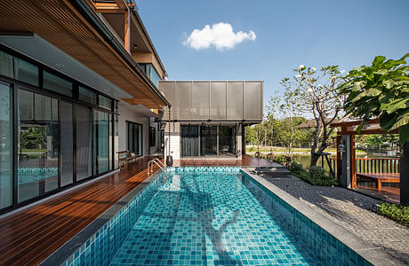 Contemporary home with pool and wood deck under clear skies.