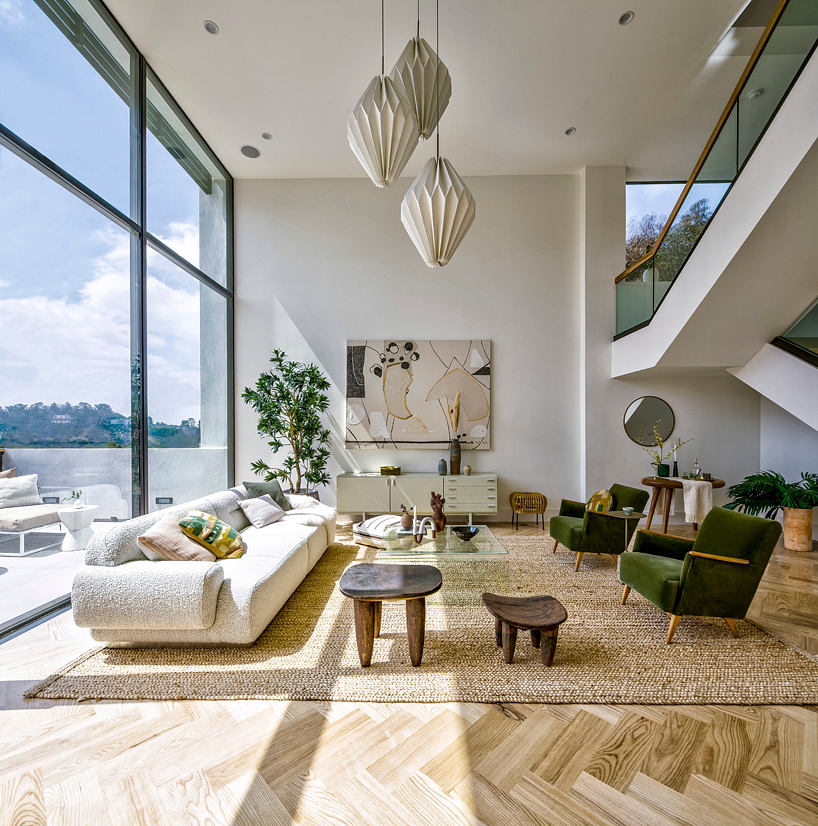 Bright living room with large windows, stylish furnishings, and chevron wood flooring.