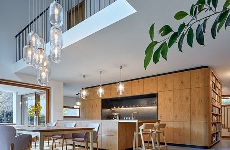 Modern kitchen with dining area, wooden cabinets, and pendant lights.