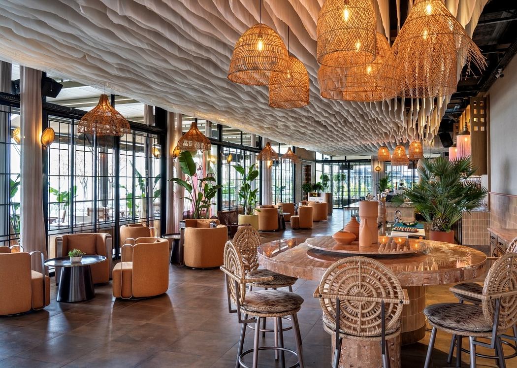 Modern restaurant interior with sculptural ceiling and wicker lamps.