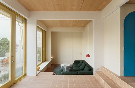 Modern minimalist living room with wooden ceiling and terracotta floor.