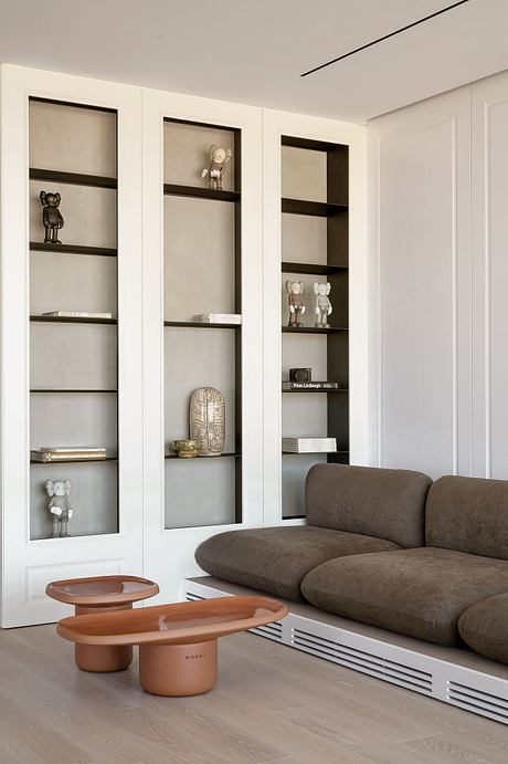 Contemporary living room with built-in shelves, brown couch and minimal decor.