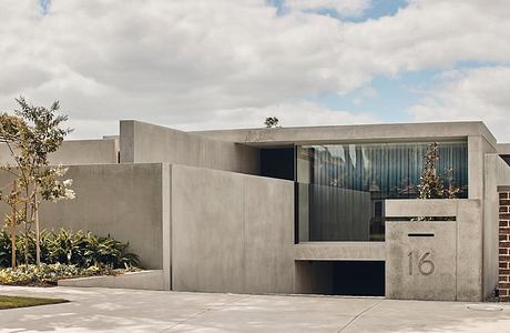 Modern concrete house with geometric design and large windows.