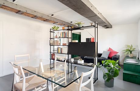 Minimalist living space with exposed beams and a glass table.