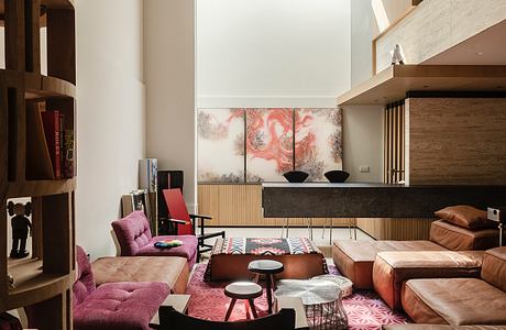 Modern living room with pink and tan furniture, large painting, and skylight