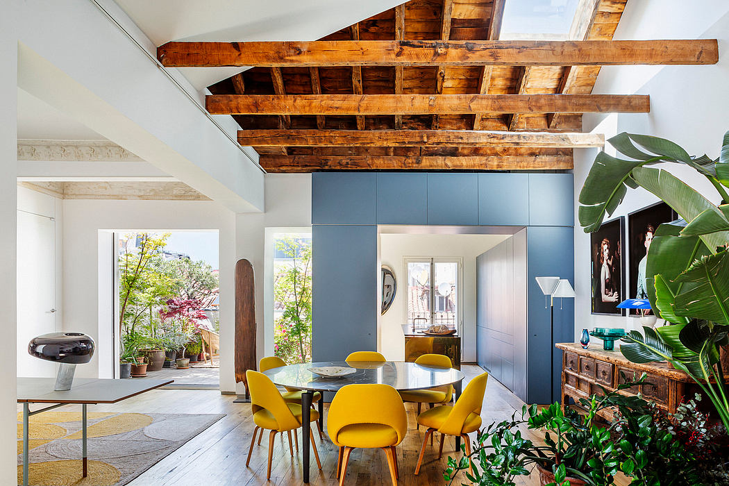Modern dining room with yellow chairs, wooden ceiling beams, and indoor plants.