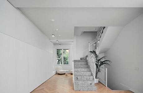 Minimalist interior with white walls, wooden floor, and gray staircase.