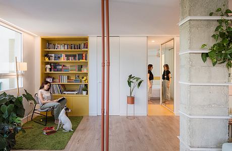 Contemporary home interior with colorful bookshelf, sliding doors, and a woman reading