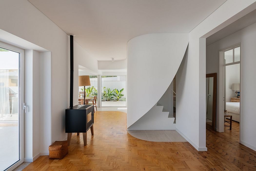 Modern interior with curved staircase, wooden flooring, and minimalistic furniture.