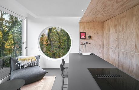 Sleek kitchen with wood accents and circular window.