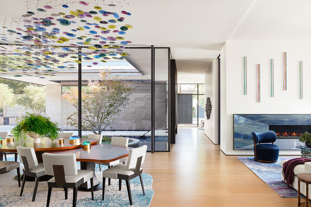 Modern dining room with colorful ceiling sculpture and fireplace.
