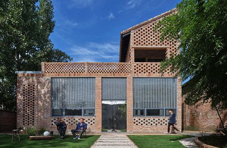 Modern brick house with patterned facade and large windows, set in a lush garden