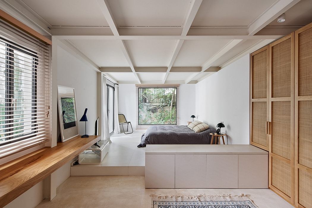 Modern minimalist bedroom with a bed, desk, and wooden cabinets.