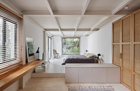 Modern minimalist bedroom with a bed, desk, and wooden cabinets.