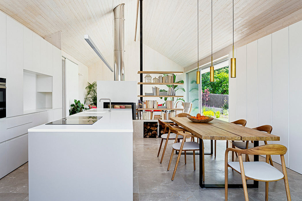Modern kitchen and dining area with white cabinets, wooden table, and pendant lights.