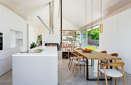 Modern kitchen and dining area with white cabinets, wooden table, and pendant lights.