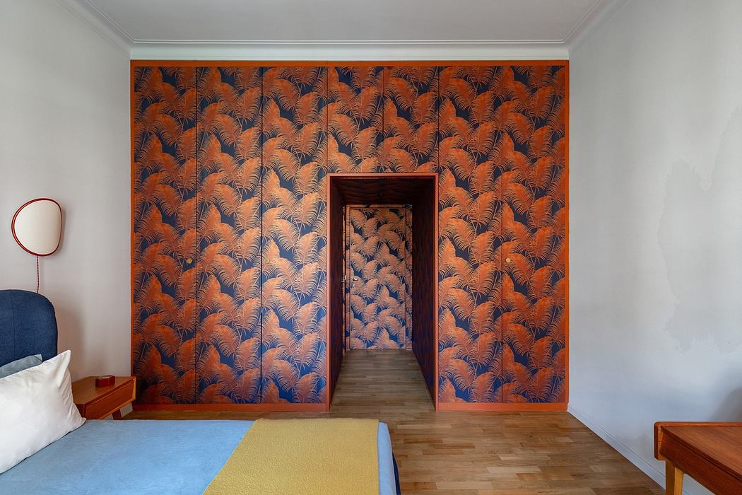 A room with a distinctive fern-patterned orange wallpaper and an open doorway.