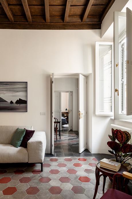 Modern room with white walls, wooden ceiling beams, and hexagonal floor tiles.