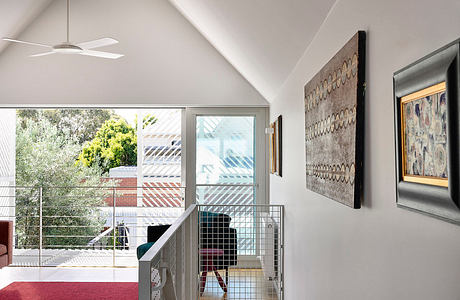 Loft-style interior with high ceiling, gallery wall, and glass railing.