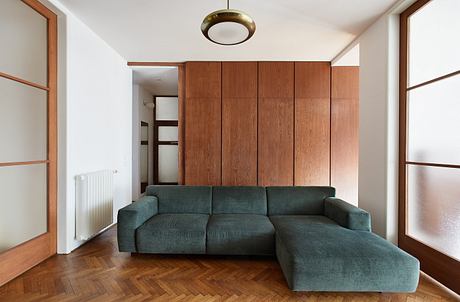 Contemporary room with wooden wall paneling and teal sectional sofa.