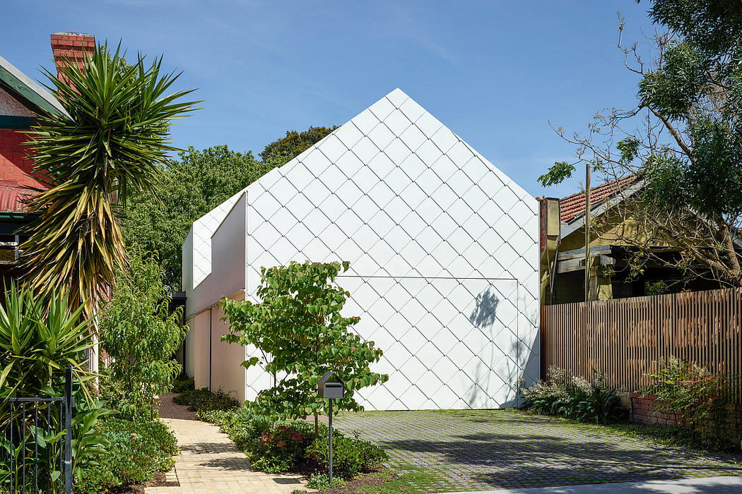 Geometric white house with a diamond-pattern facade surrounded by greenery.