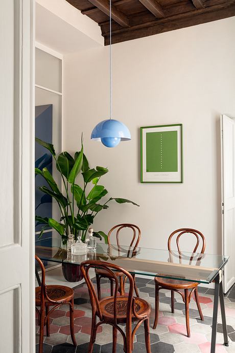 Modern dining room with glass table, bentwood chairs, blue pendant light, and