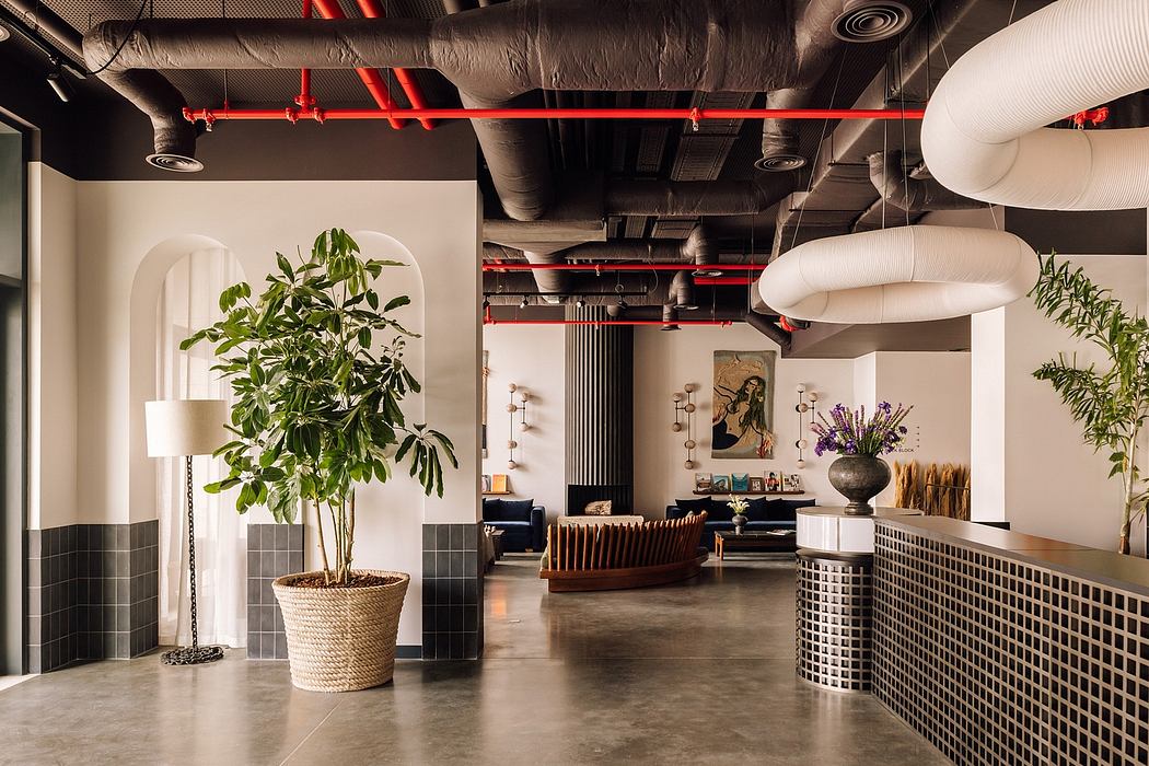Modern office interior with exposed red pipes, ductwork, and stylish furniture.