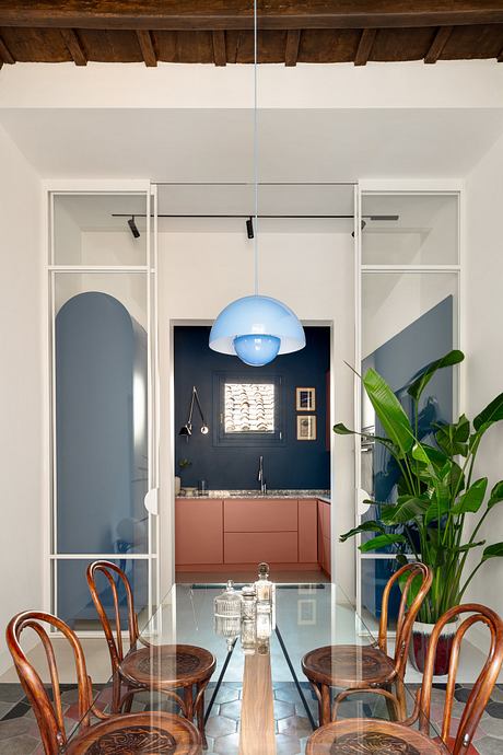 Elegant dining area with wooden table, bentwood chairs, and a blue pendant