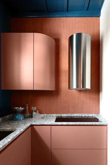 Modern kitchen with pink cabinets, terracotta walls, and blue ceiling.