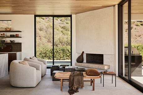 Modern living room with sleek furniture and large windows overlooking nature.