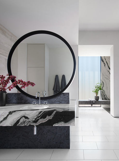 Modern bathroom with marble sink, large round mirror, and minimalist decor.