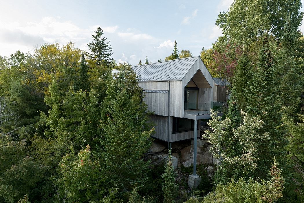 Modern cabin on stilts nestled in a forest.