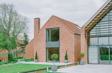 Modern brick house with large glass windows and manicured lawn.