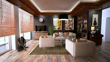 Modern living room with beige furniture, a TV, and wooden floors.