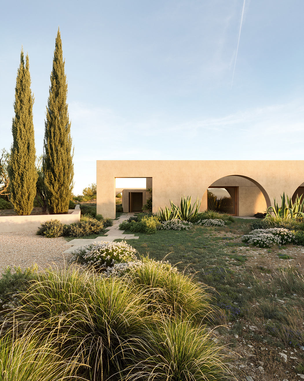 Contemporary building with arches, surrounded by desert landscaping and tall cypress trees