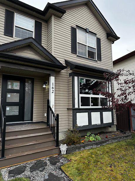 Suburban two-story home with beige siding and a small porch.