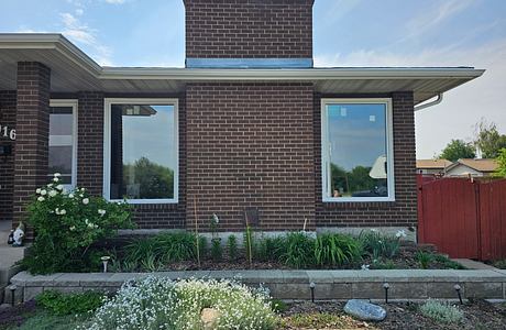 Brick house with large windows and landscaped garden.