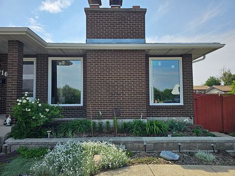 Brick house with large windows and landscaped garden.