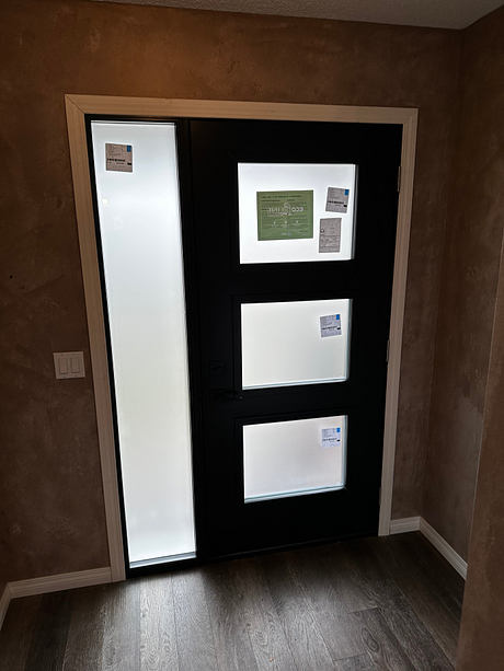 Modern black door with three white panels and vertical glass window in a room with brown