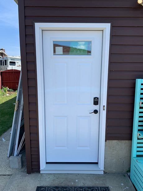 White residential front door with a digital lock on a brown house facade.