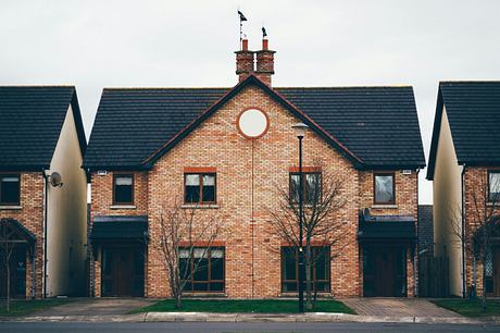 Symmetrical brick houses with central round window and bare trees.