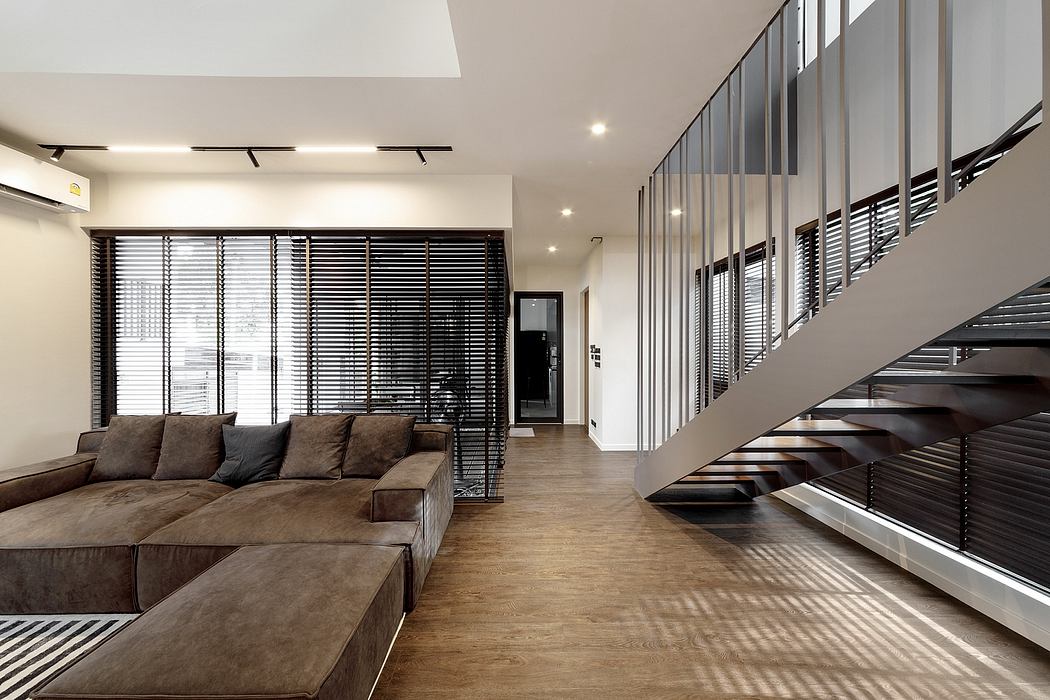 Contemporary living space with sectional sofa and sleek staircase.